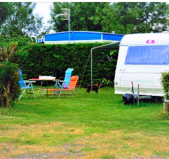 Caravane et mobilier de camping sur herbe verte.
