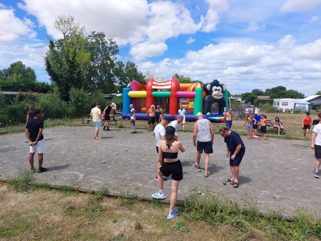 Personnes jouant à la pétanque près d'un château gonflable.