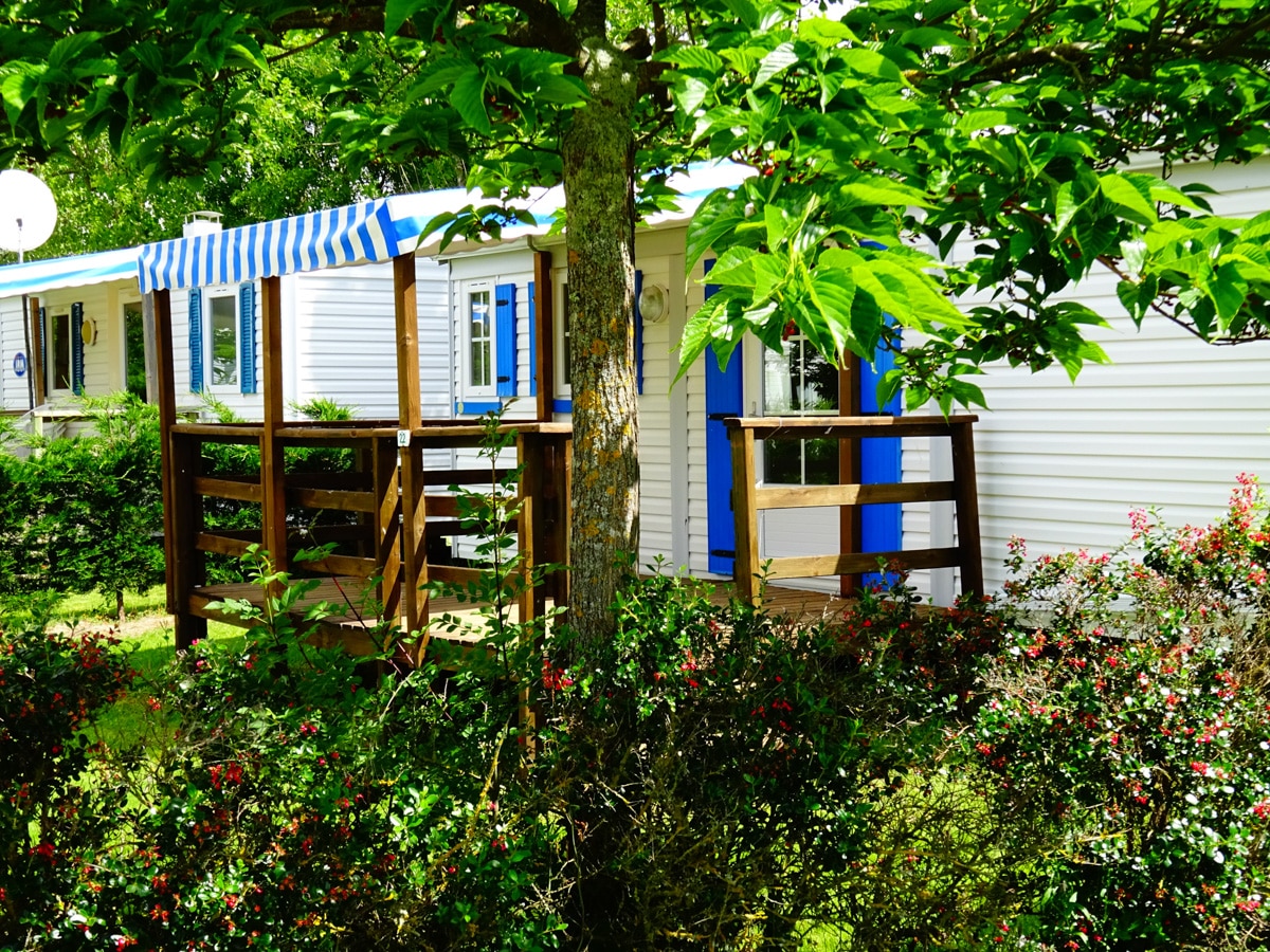 Mobil-home avec terrasse en bois entouré de verdure, camping près de Moutiers-les-Mauxfaits