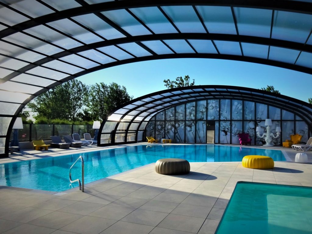 Piscine couverte moderne avec jacuzzi et chaises longues.