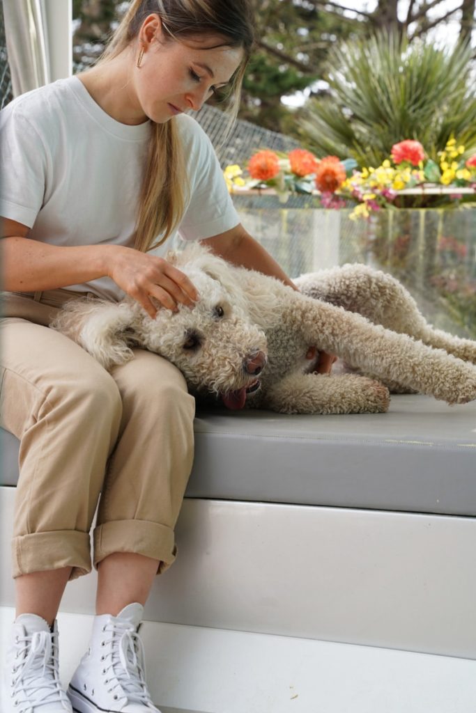 Femme câlinant un chien sur un canapé extérieur.