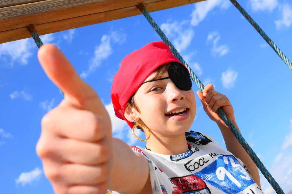 Enfant déguisé en pirate souriant avec pouce levé.