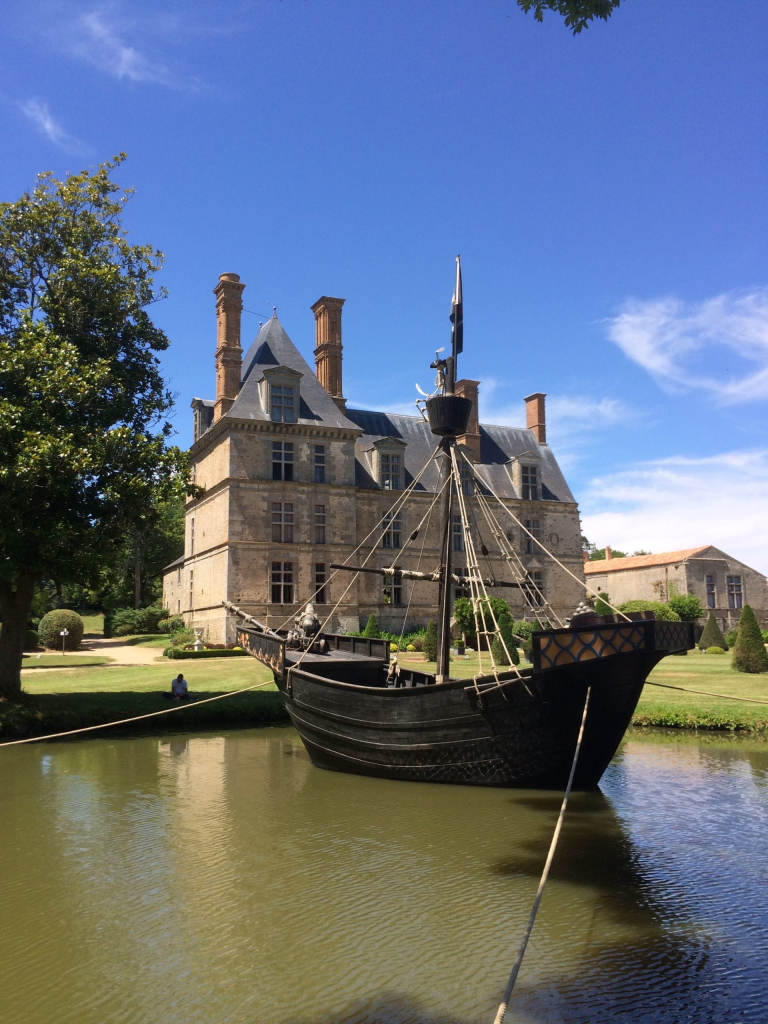 Château français avec réplique de navire médiéval.