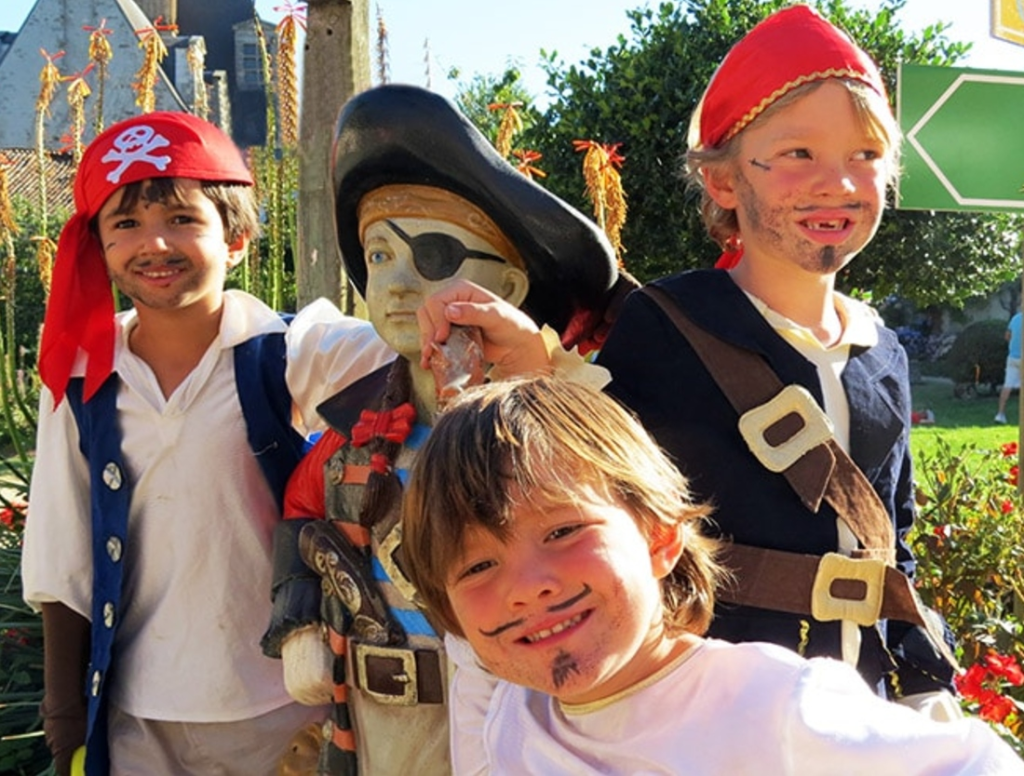 Enfants déguisés en pirates souriant en extérieur.