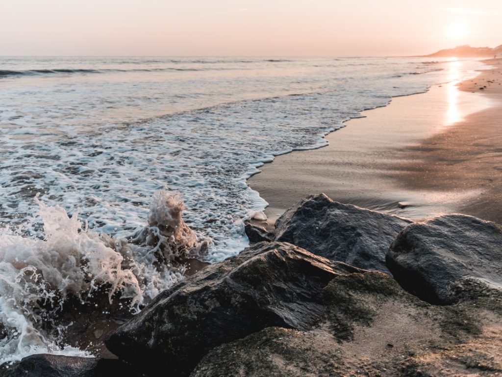 Coucher de soleil sur plage et rochers.