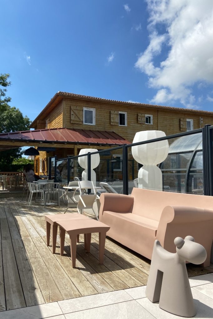Terrasse en bois avec meubles modernes, ciel bleu.