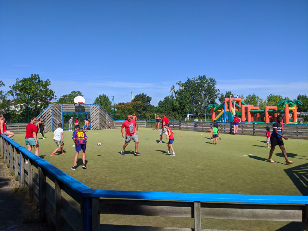 Enfants et adultes jouant au football en extérieur.
