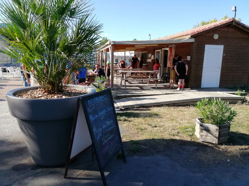 Terrasse de restaurant avec clients et ardoise de menu.
