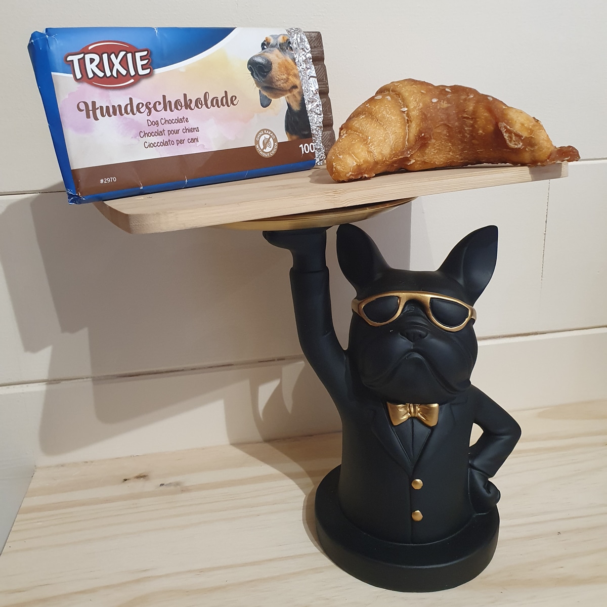 Statue chien serveur avec chocolat et croissant.