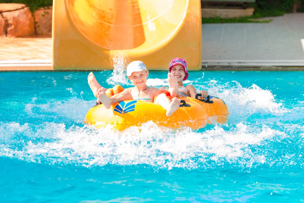 Enfants souriants sur bouée à la piscine.