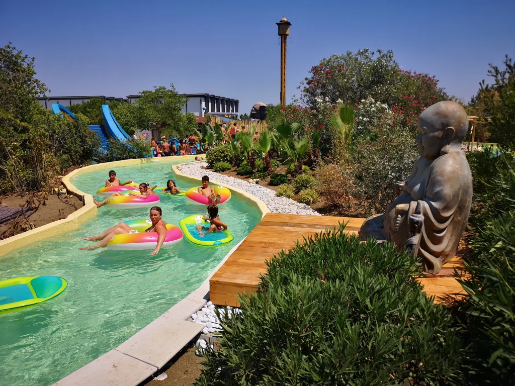 Lazy river avec bouées et statue dans parc aquatique.