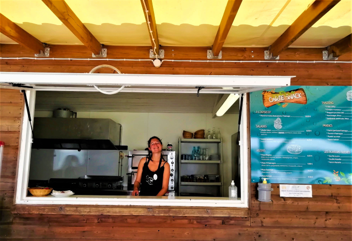 Femme souriante dans un stand de nourriture en bois.