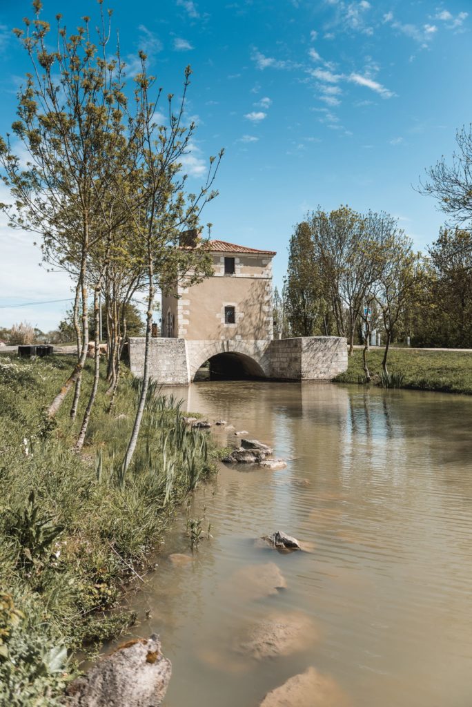 Maison près d'une rivière et pont, ciel dégagé.