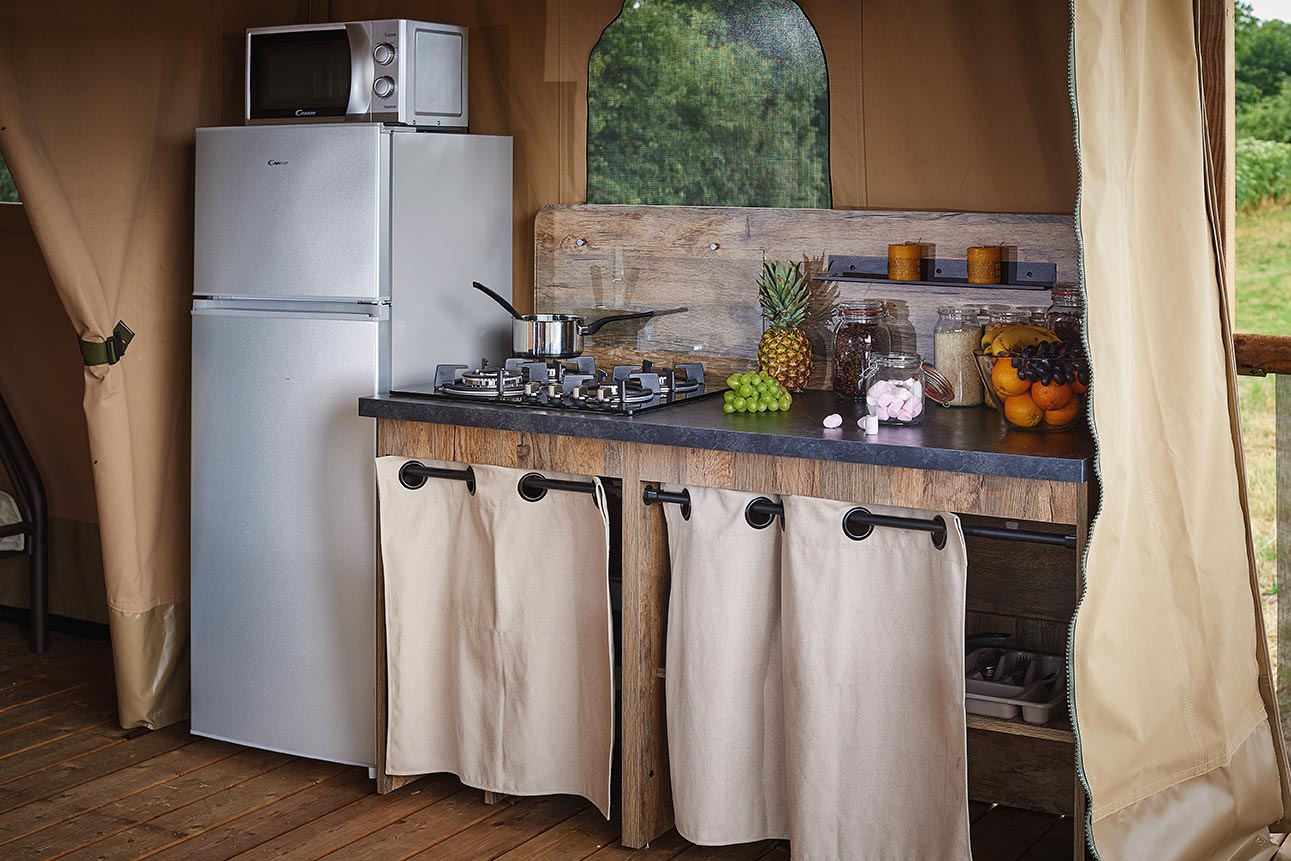 Camping kitchen with fridge and tropical fruit.