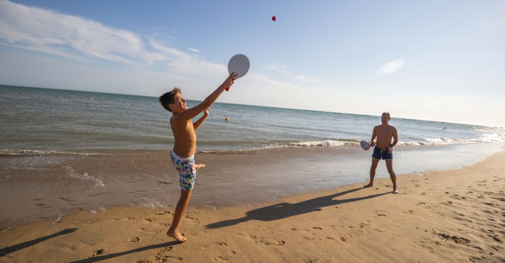 Deux personnes jouent au ballon sur la plage.