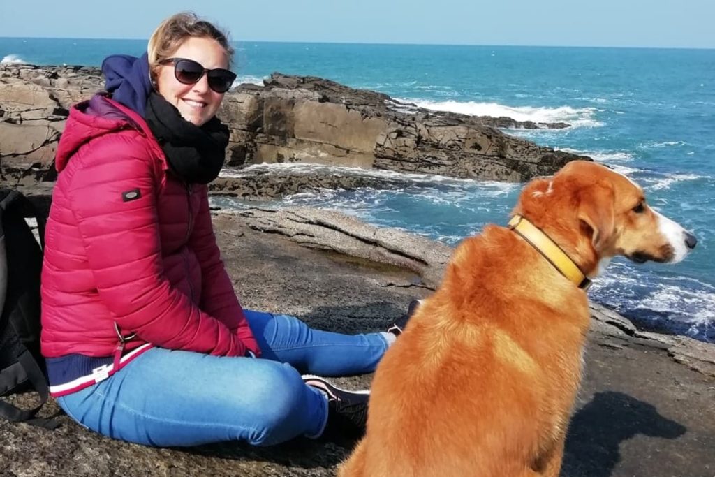 Femme et chien sur rochers près de la mer.