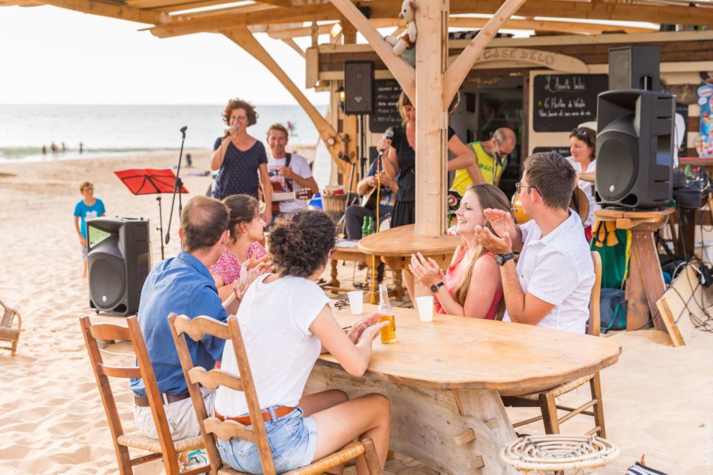 Groupe applaudissant un concert sur la plage.