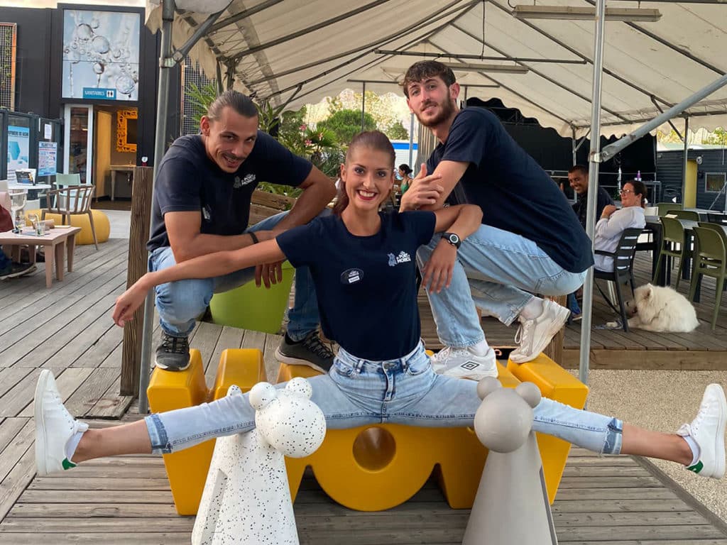 Trois jeunes posent joyeusement dans un café en plein air.