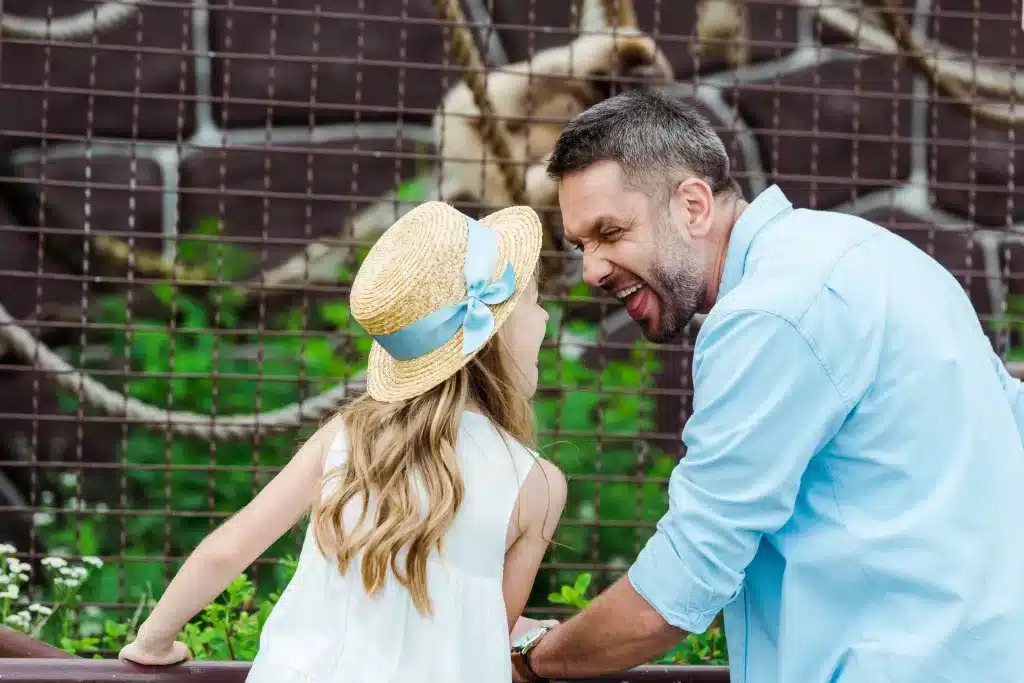 Father and daughter smiling together at the zoo.